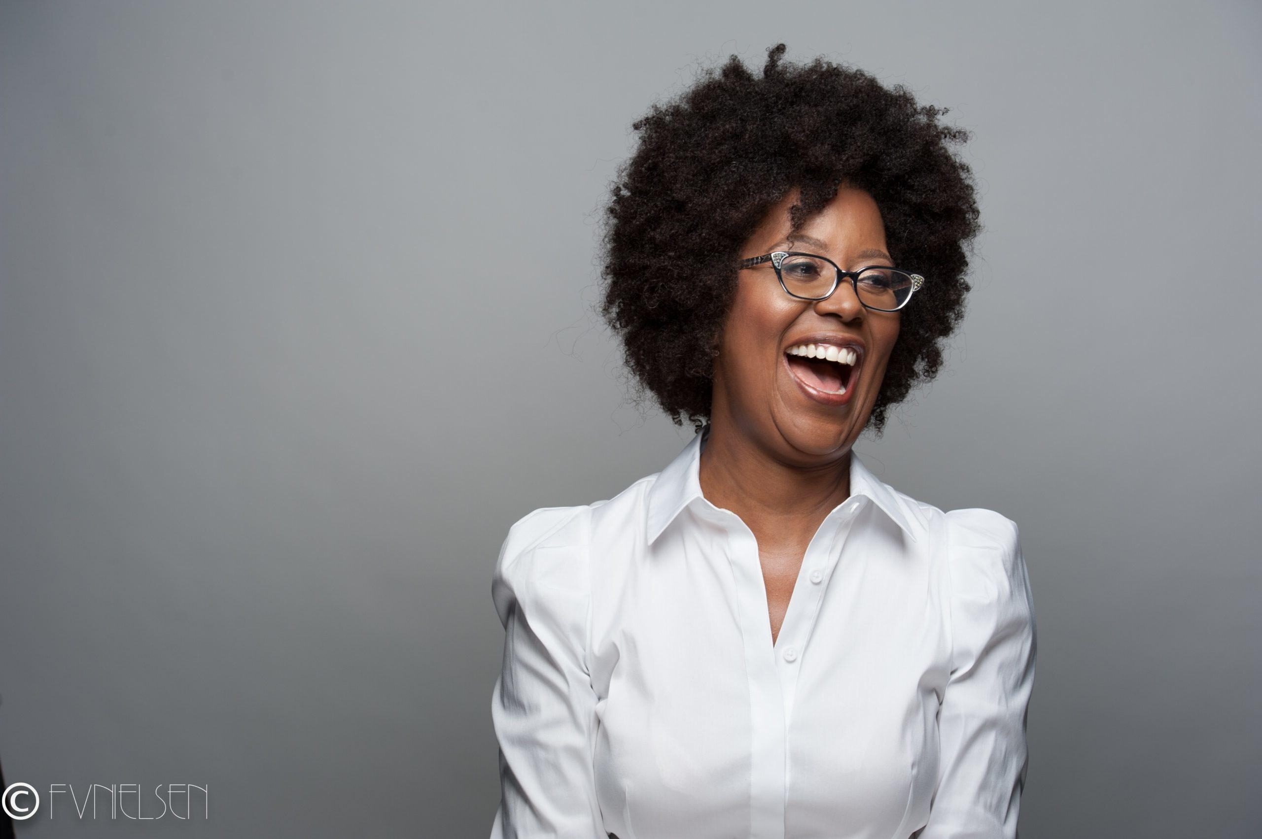 Jacquette Timmons in a white shirt looking left and laughing