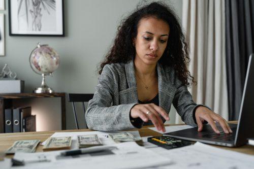 woman of colour with adding machine looking stressed about money