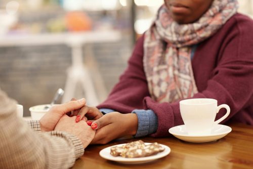 two people holding hands next to a coffee cup.